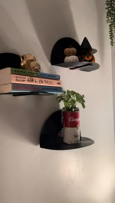 three shelves with books and plants on them in a corner next to a white wall