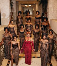 a group of women in brown dresses standing on stairs with one woman wearing a red dress