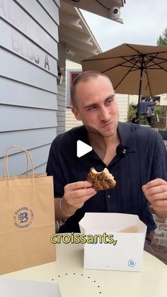 a man holding a piece of food in front of his face while sitting at a table