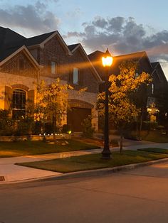 a street light sitting in front of a row of houses at night with the lights on