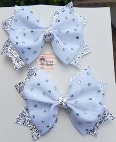 three blue bows with silver sequins on them sitting on top of a white box