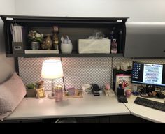 a desk with a computer, lamp and other items on top of it in an office