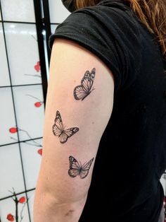 a woman's arm with three butterflies tattooed on the back of her left arm