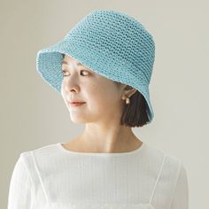 a woman wearing a blue crochet hat and white shirt with her eyes closed