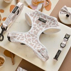 a white and brown dog harness sitting on top of a table next to bowls of food