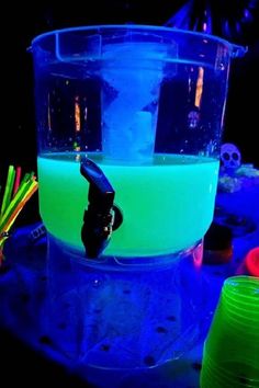 a blue and green liquid in a plastic container with neon colored straws around it