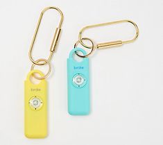 two key chains that are attached to some type of device on a white surface and one has a camera in it