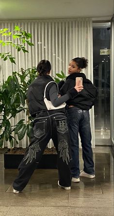 two people standing in front of a plant