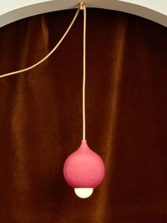 a pink light hanging from a brown curtain