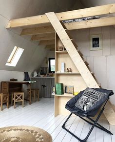 an attic loft with stairs leading up to the loft bed and desk in front of it