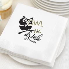 a napkin with an owl on it sitting next to some plates and cupcakes