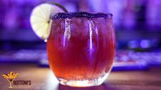 a close up of a drink on a table with a lime wedged in it