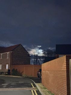 an empty street at night with dark clouds in the sky