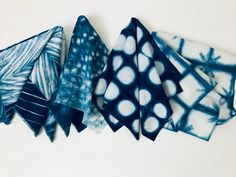 five pieces of blue and white tie - dyed fabric are arranged in a row on a white surface