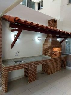 an outdoor kitchen with brick walls and tile counter tops, under a wooden beam over the sink