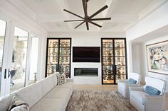 a living room with couches, chairs and a ceiling fan in front of a fireplace