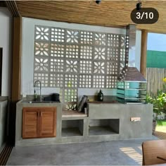 an outdoor kitchen made out of concrete and wood with decorative screens on the wall behind it