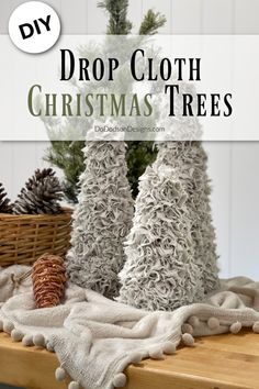 christmas trees made out of yarn and pine cones are sitting on a table with the words drop