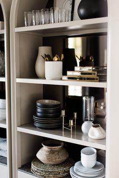 the shelves are filled with dishes and cups, plates, vases and other items