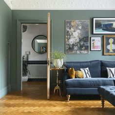 a living room with blue couches and pictures on the wall above them in various frames