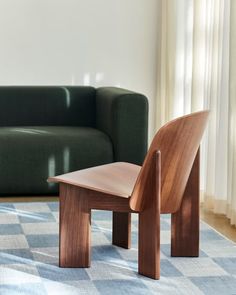 a wooden chair sitting on top of a blue rug in front of a green couch