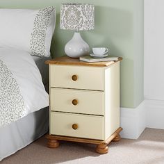 a nightstand with two drawers next to a bed