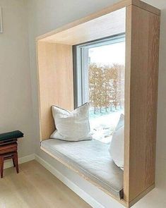 a window seat in the corner of a room with pillows and a pillow on it