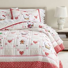 a hello kitty comforter set on a bed with red and white bedspread