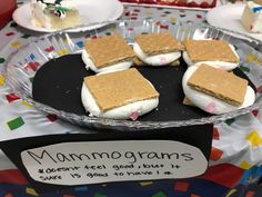 there are many desserts on the table with name tags in front of them, including marshmallows and graham crackers