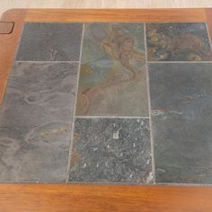 a wooden table topped with lots of different types of slate tiles on top of it