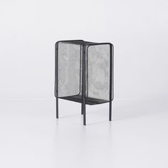 a black mesh screen sitting on top of a white floor in front of a wall