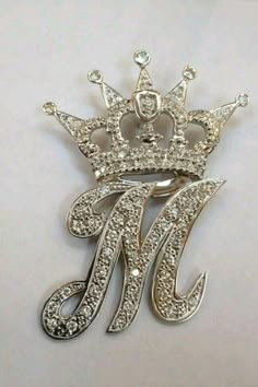 a silver brooch with a crown on it's head and the letter m