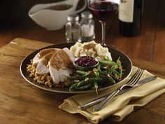 a plate with meat, mashed potatoes and green beans next to a glass of wine