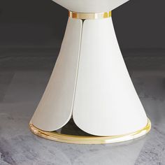 a white table with gold trim on it and a vase in the middle that is shaped like a cone