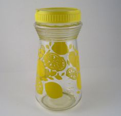 a glass jar with lemons and limes painted on the lid, sitting on a white surface