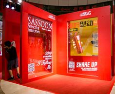 a red booth with advertisements on it and people standing in the doorway looking at them