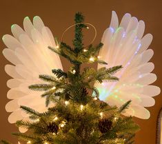 a small christmas tree with angel wings on it's top and lights around the base