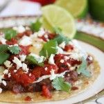 a close up of a taco on a plate with tomatoes and cilantro