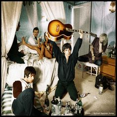 a group of people sitting on top of a bed next to each other with guitars