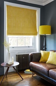 a living room filled with furniture and a yellow window shade on the window sill