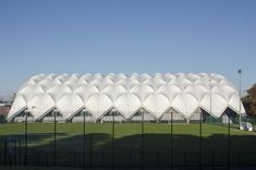 a large white building sitting on top of a lush green field next to a soccer field