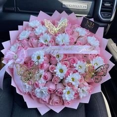 a bouquet of pink roses and white daisies in the back seat of a car