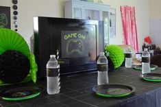 a table topped with plates and water bottles next to a flat screen tv on top of a black counter