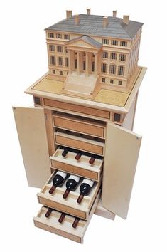 a wooden model of a house with drawers and wine bottles in the bottom drawer that is open