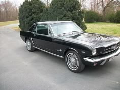 an old black car is parked on the street