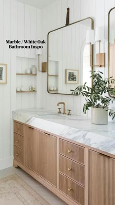 a bathroom with white walls, wooden cabinets and a large mirror on the wall above it