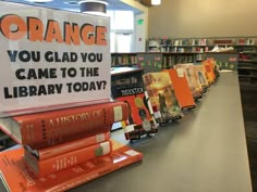 there are many books lined up in the library with orange signs on them that read, you glad you came to the library today?