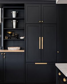 a kitchen with black cabinets and gold handles