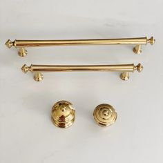 three brass handles and two knobs on a white surface