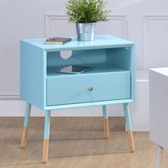 an end table with a potted plant on top and a phone in the drawer